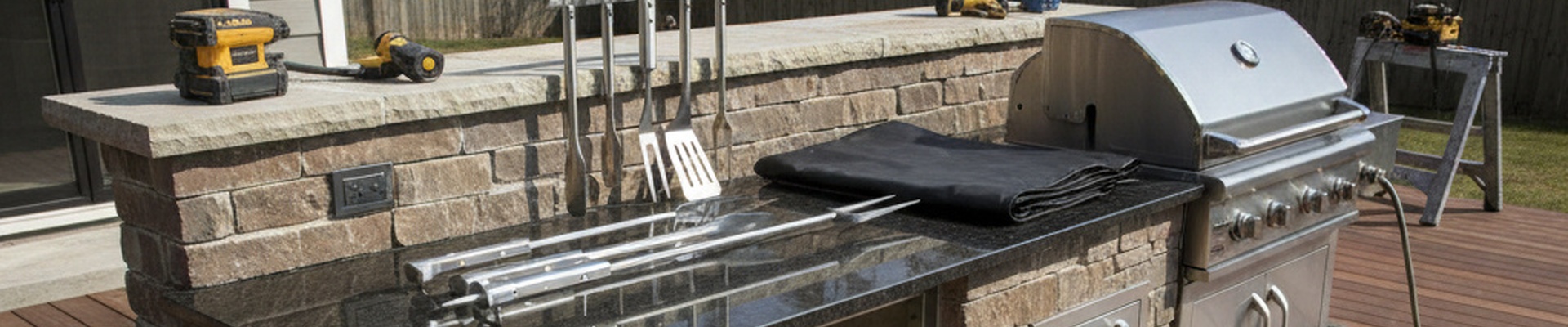 Grill Components - Outdoor kitchen island being built with tools, grill cover, and accessories